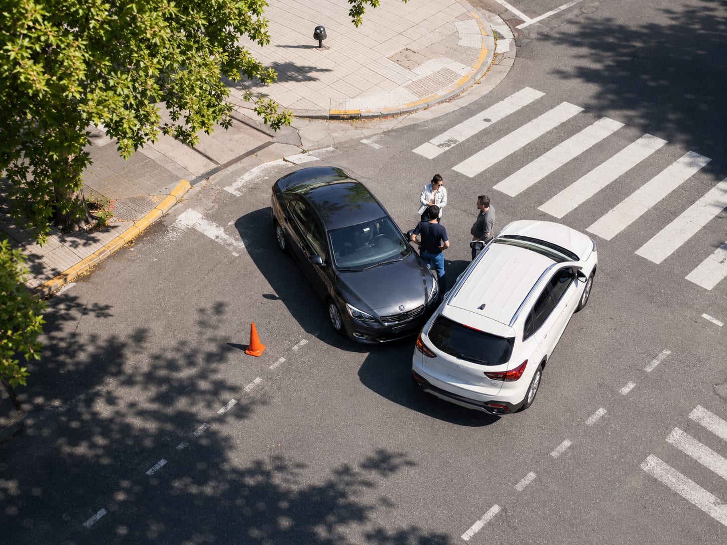 Vista aérea de dos autos detenidos tras un choque en una intersección; tres personas conversan junto a ellos